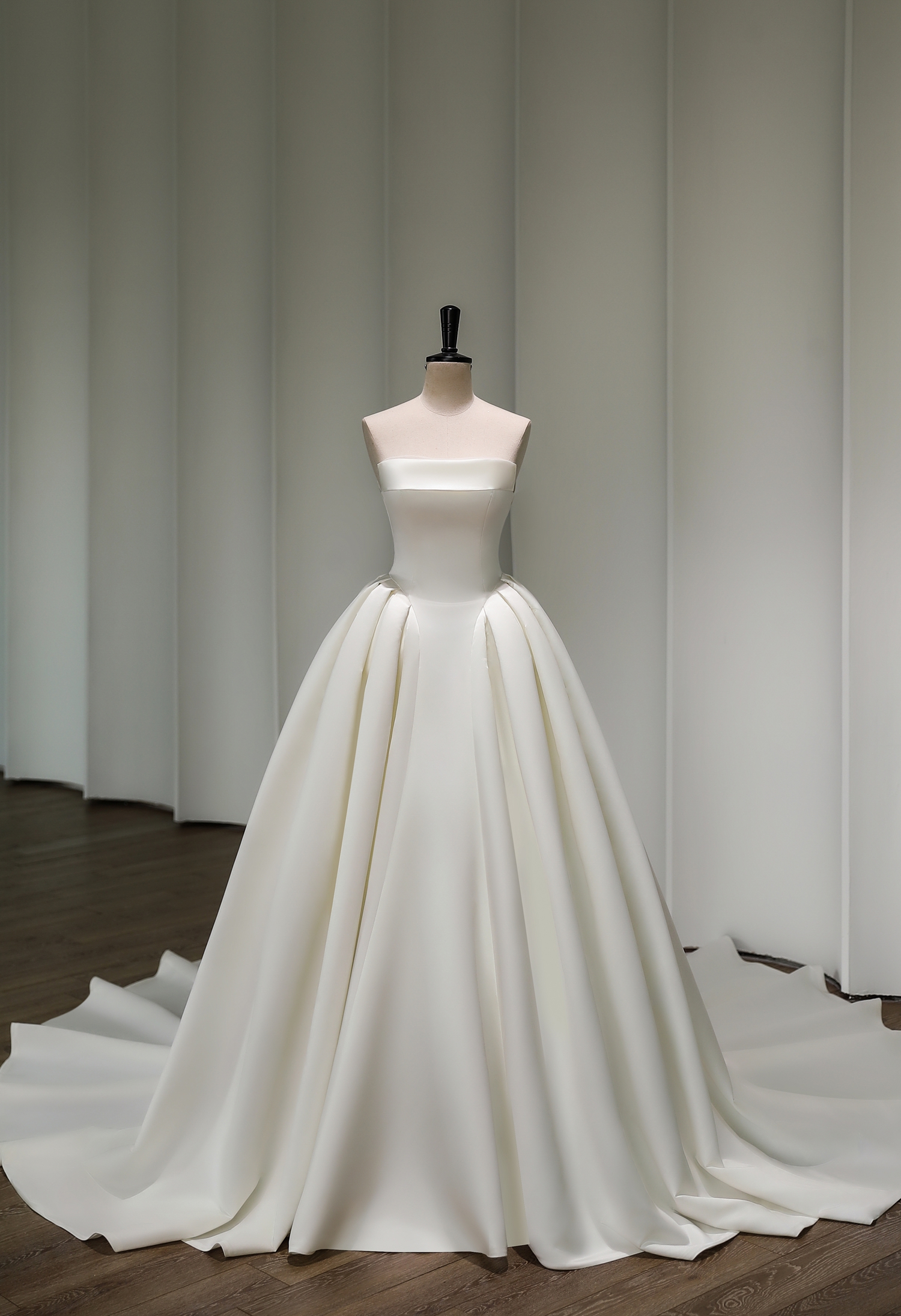 A classic strapless satin ball gown with a sculpted bodice and pleated skirt. Perfect for brides craving minimalist luxu