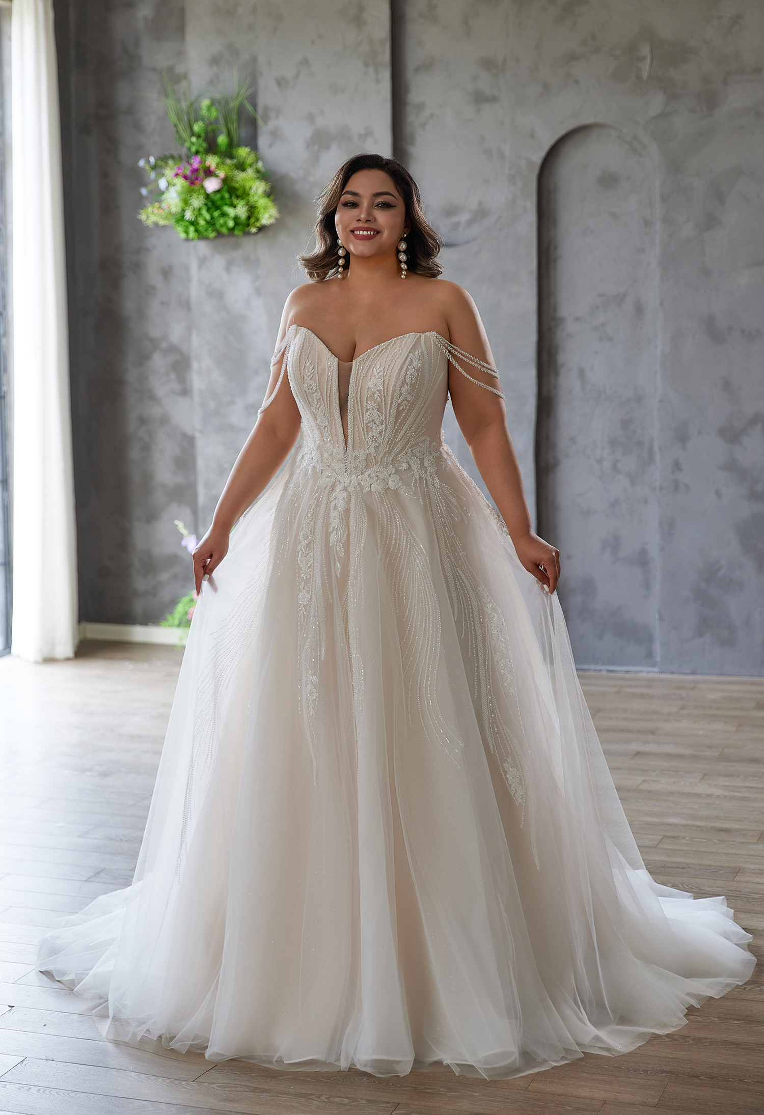Off-shoulder A-line gown with cascading beadwork and tulle skirt. The sparkle and movement create a graceful, glamorous 