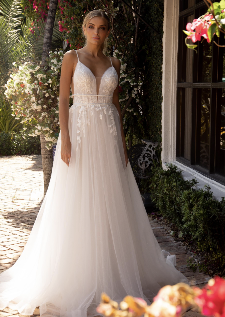Whimsical yet effortlessly refined, this A-line gown features a plunging lace bodice, delicate spaghetti straps, and a f