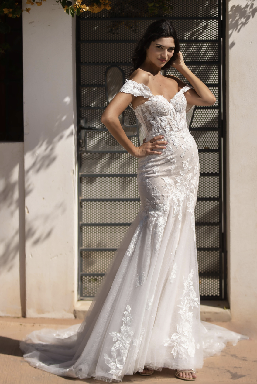 This off-the-shoulder lace wedding gown features a sculpted bodice, illusion details, and a romantic fit-and-flare silho