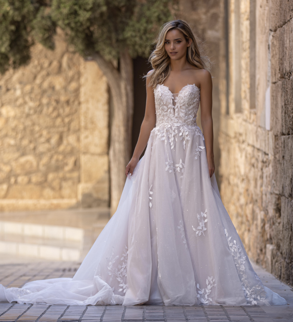 A breathtaking strapless ball gown featuring floral lace appliqués, subtle sparkle, and a romantic corset-inspired bodic