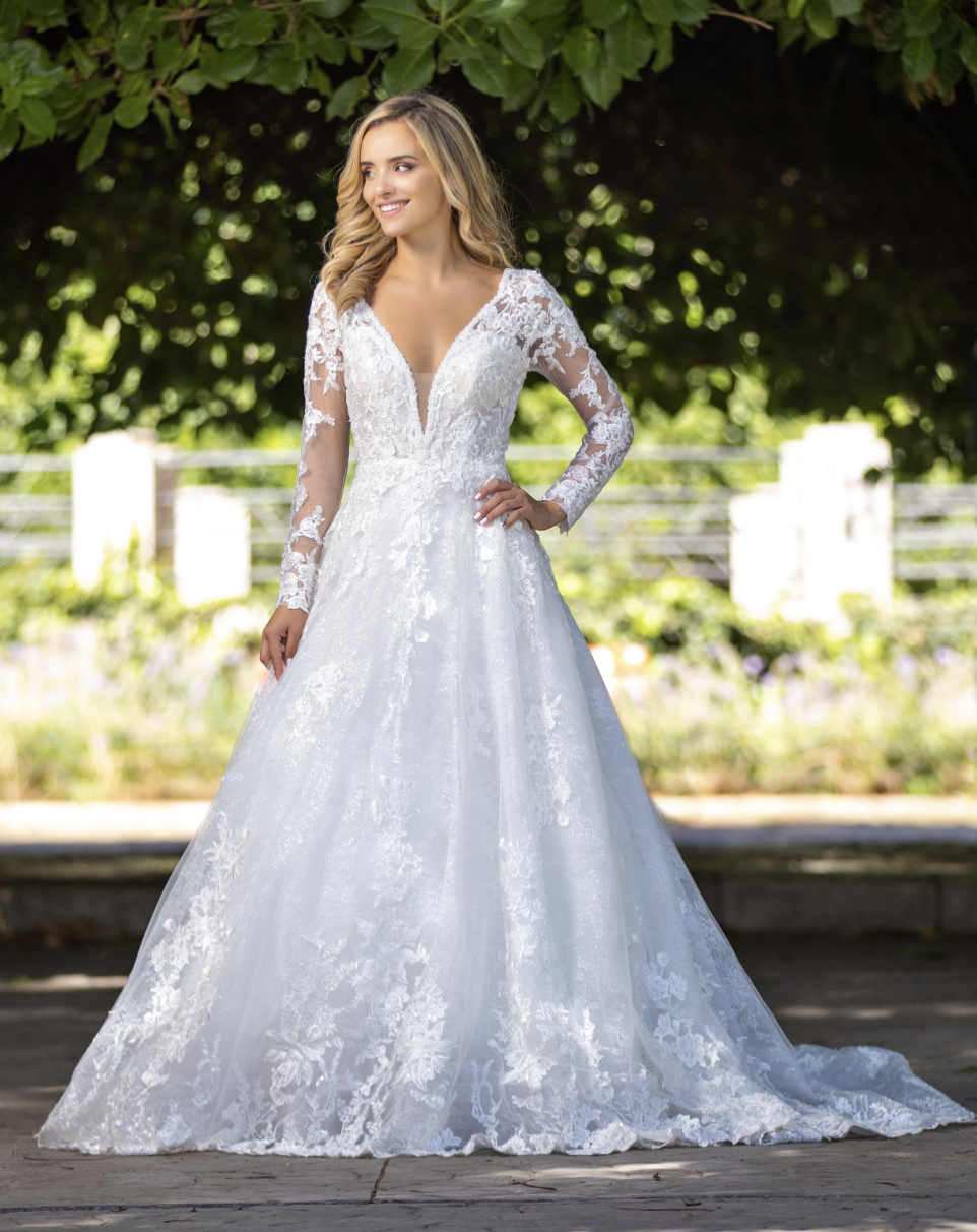 This romantic long-sleeve A-line gown features delicate floral lace, a deep illusion neckline, and a soft flowing skirt 