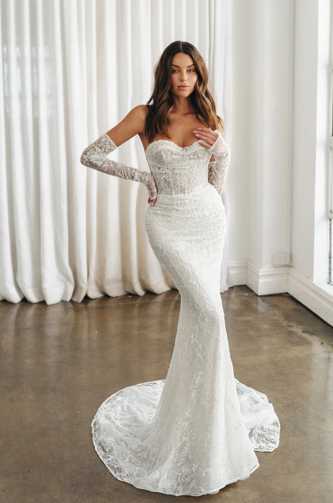Sleek, structured, and absolutely unforgettable. This strapless lace wedding gown features a sculpted corset bodice and 