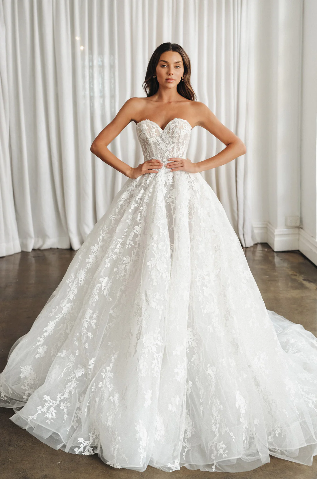 This breathtaking long-sleeve lace gown is pure romance. Featuring a high neckline, illusion bodice, and delicate floral