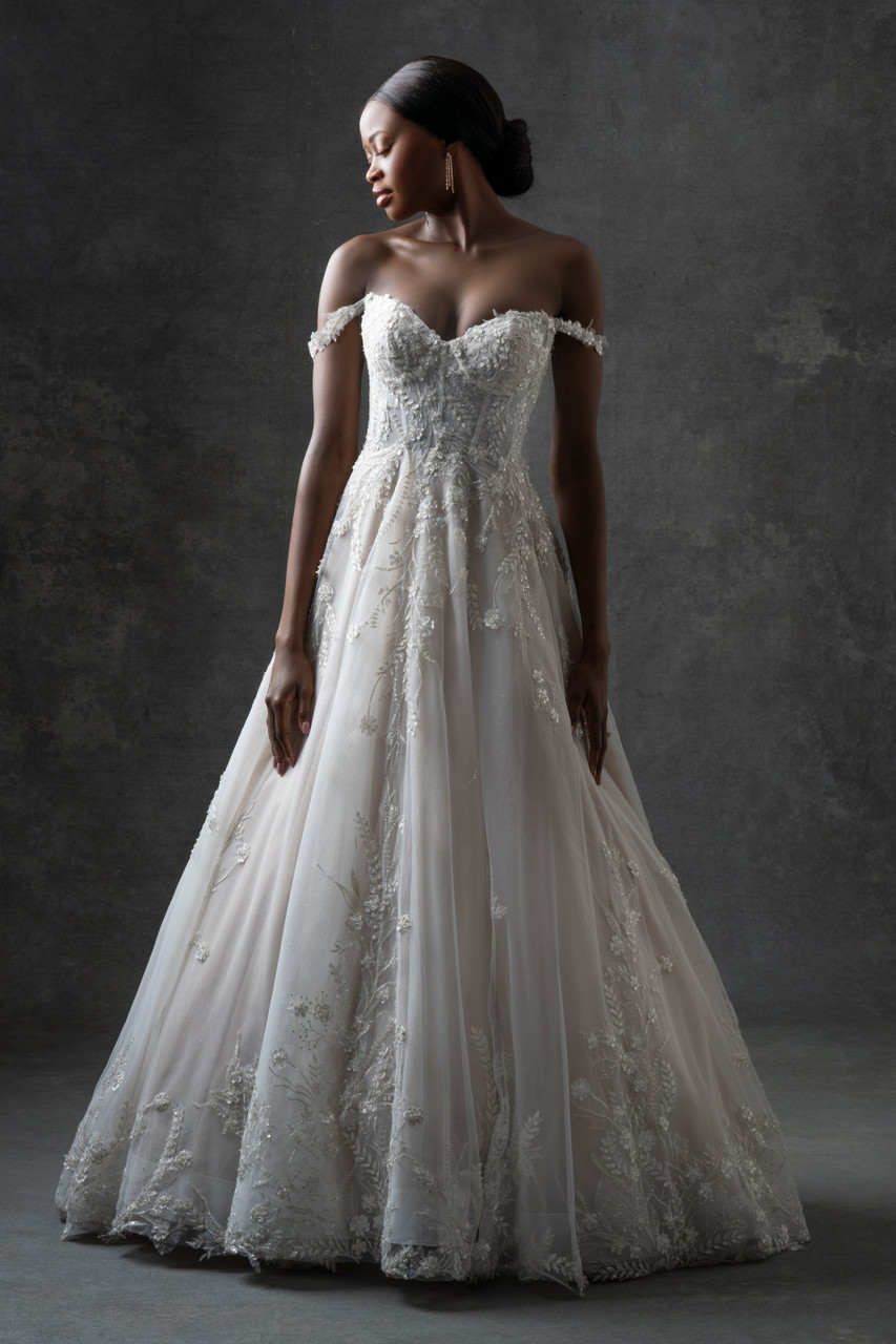 A romantic off-shoulder ball gown featuring intricate lace appliqués and shimmering tulle layers. The corset bodice and 