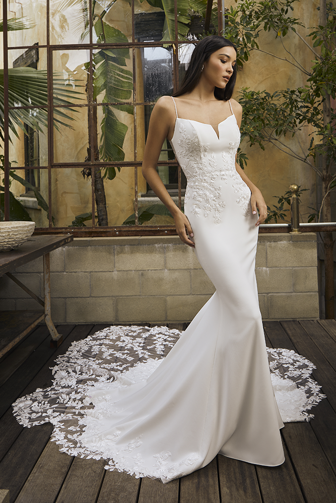 Sleek and romantic, this fitted crepe wedding gown features delicate floral appliqués and a breathtaking lace train. Wit