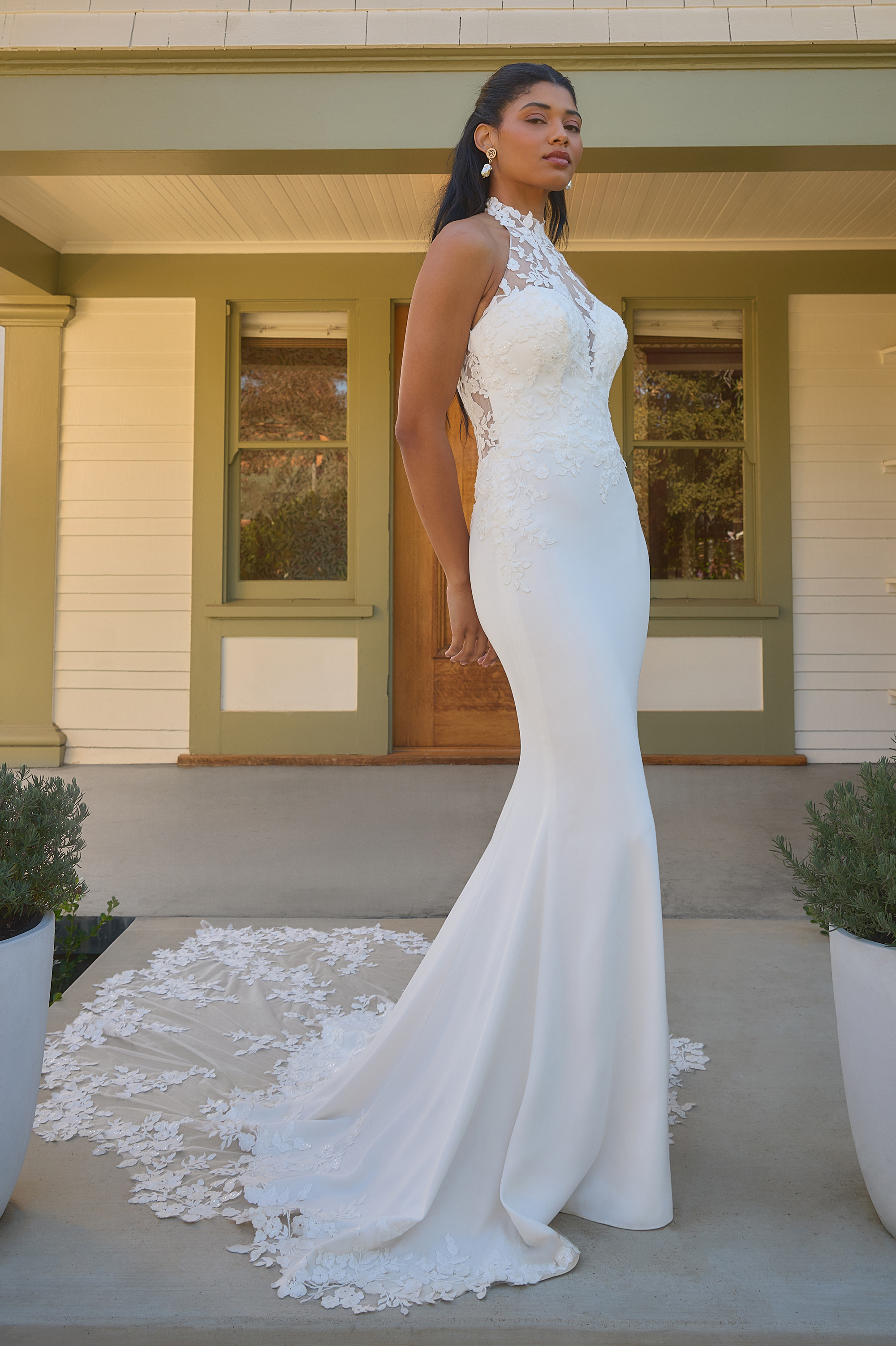 This elegant halter wedding gown features delicate lace detailing, a fitted crepe silhouette, and a stunning chapel-leng