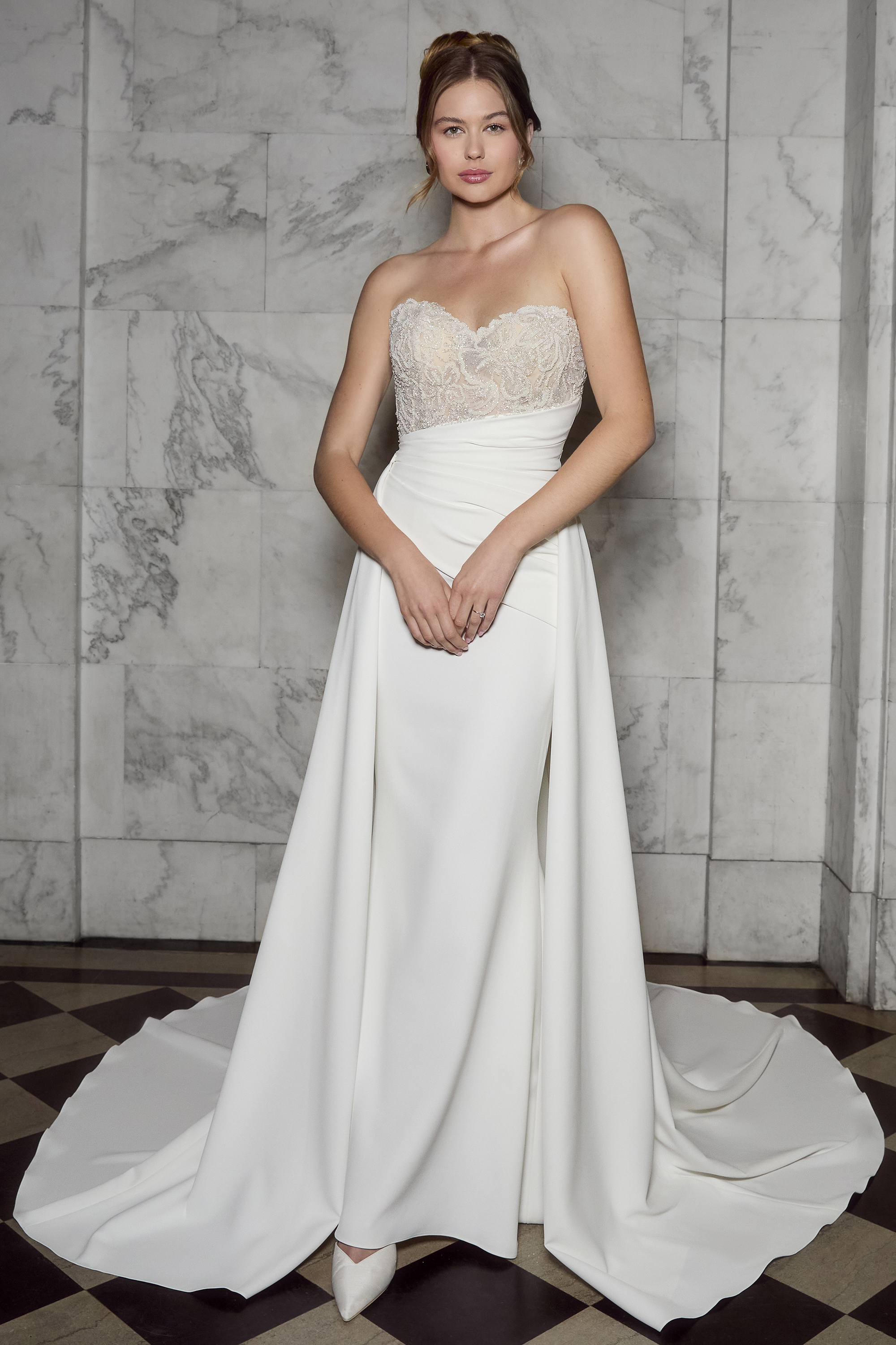 This strapless gown blends modern minimalism with timeless elegance. Featuring a delicately beaded bodice and a sleek dr