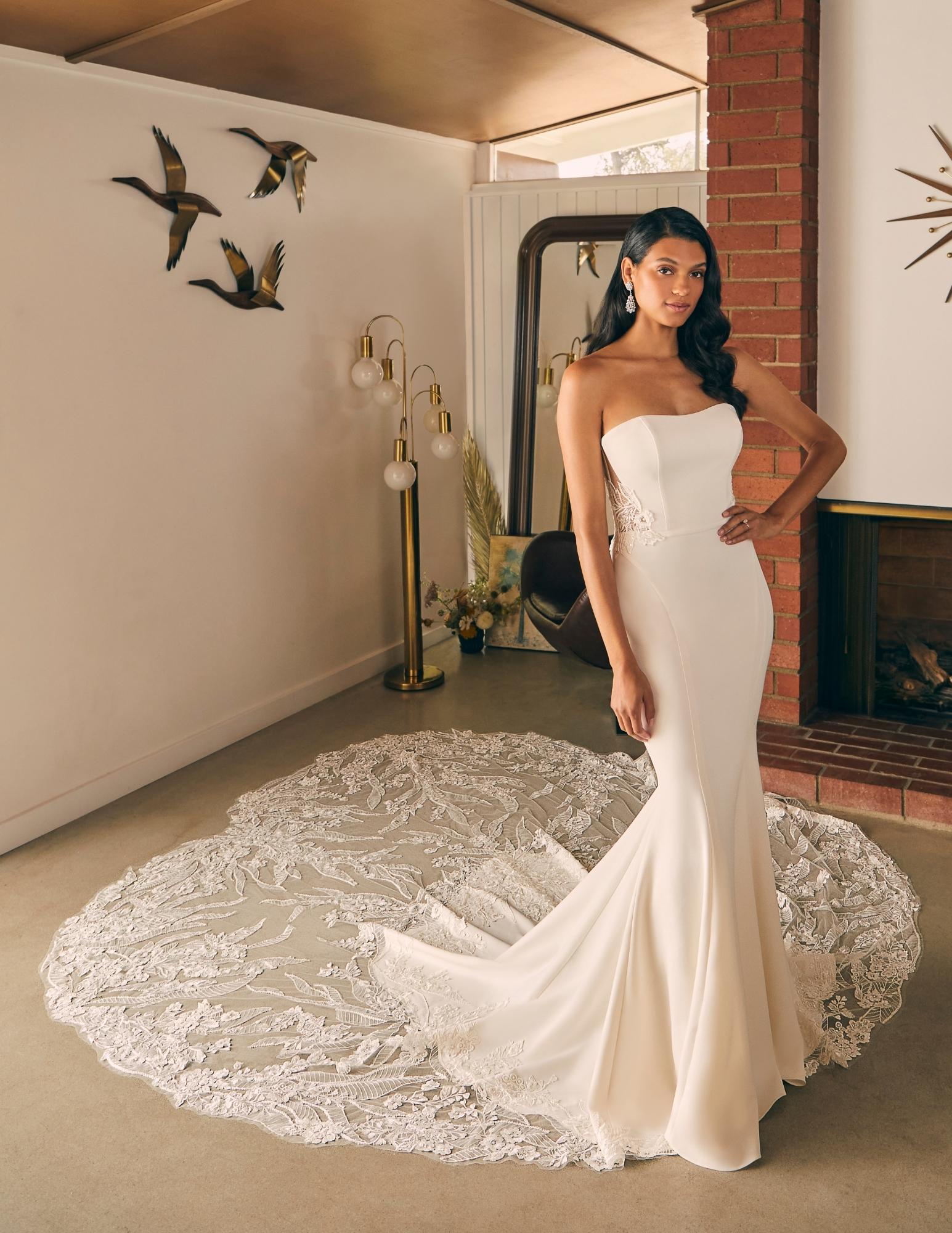 Sleek and romantic, this strapless crepe wedding dress features a fitted silhouette and a breathtaking lace train that a