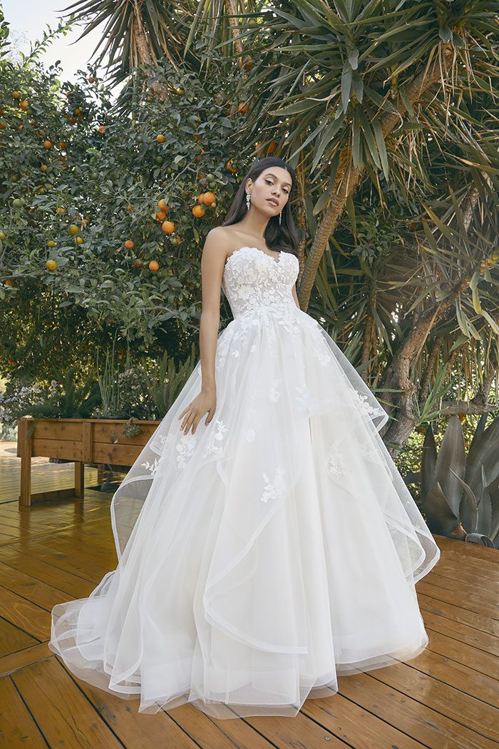 Whimsical and romantic, this fairytale-inspired ball gown features sheer puff sleeves, 3D floral lace, and cascading lay