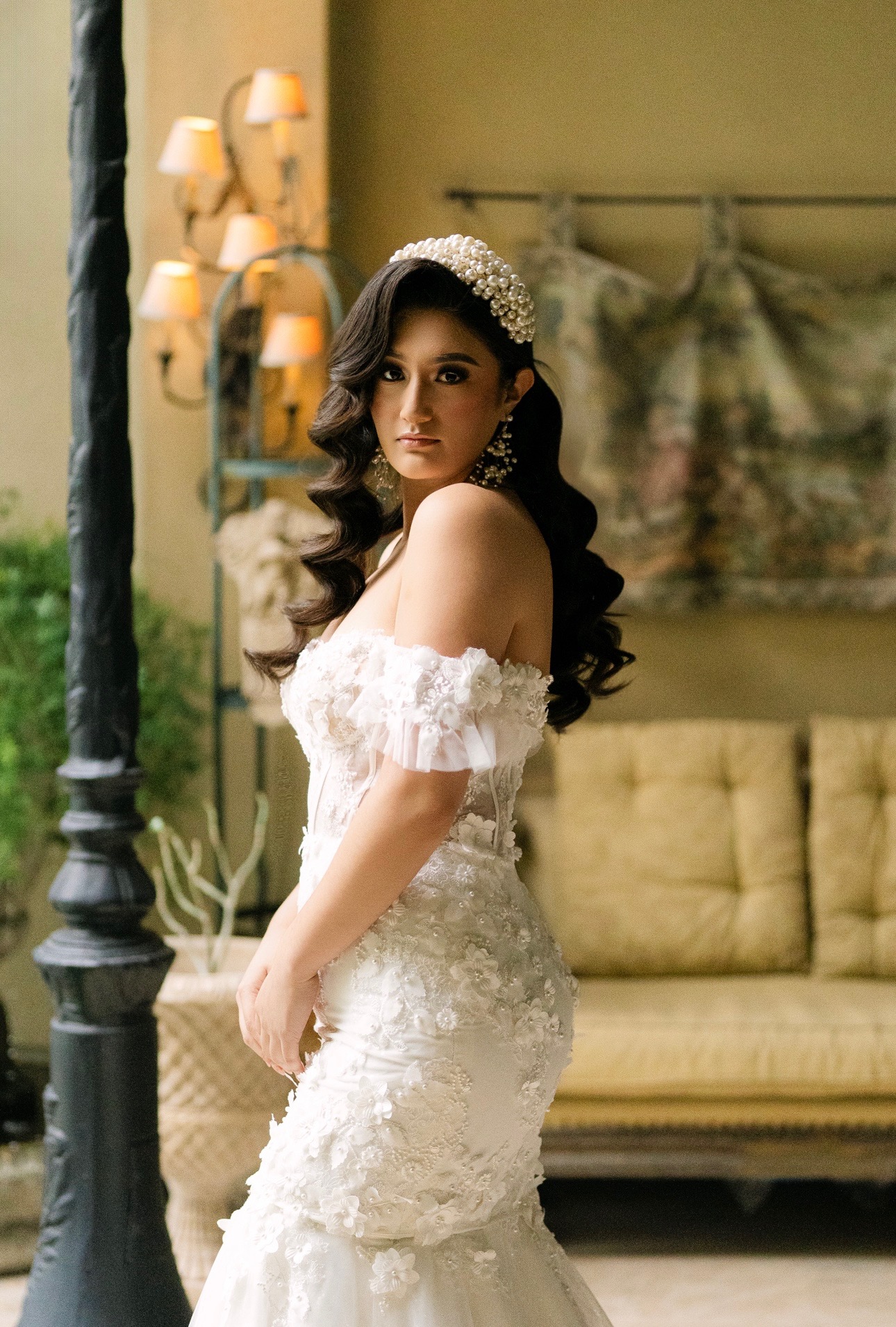 A romantic masterpiece, this off-the-shoulder mermaid gown features 3D floral lace, sheer corset detailing, and soft ruf