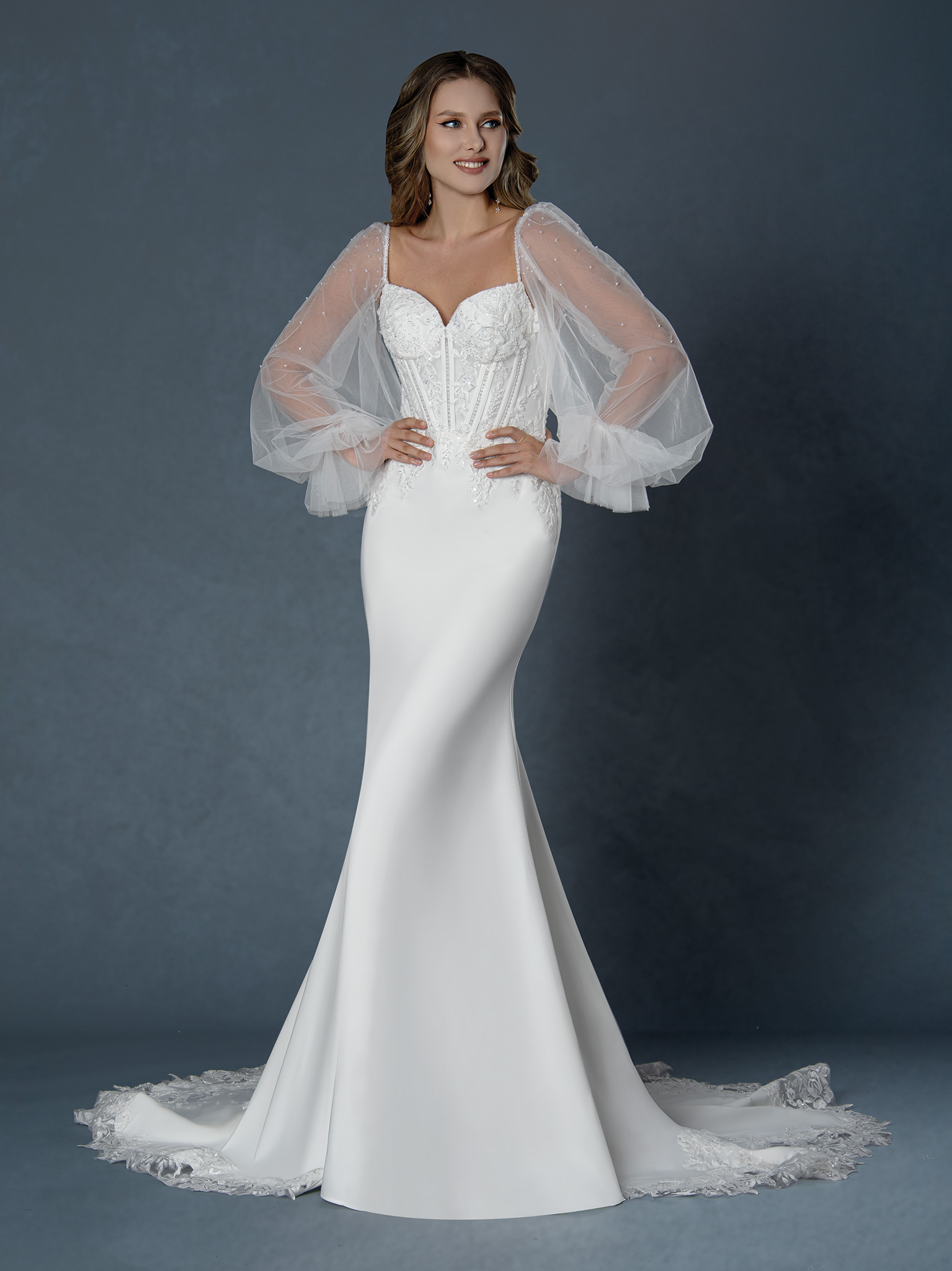 Playful yet refined, this stunning gown features dreamy pearl-dotted tulle sleeves, a sculpted corset bodice, and a slee