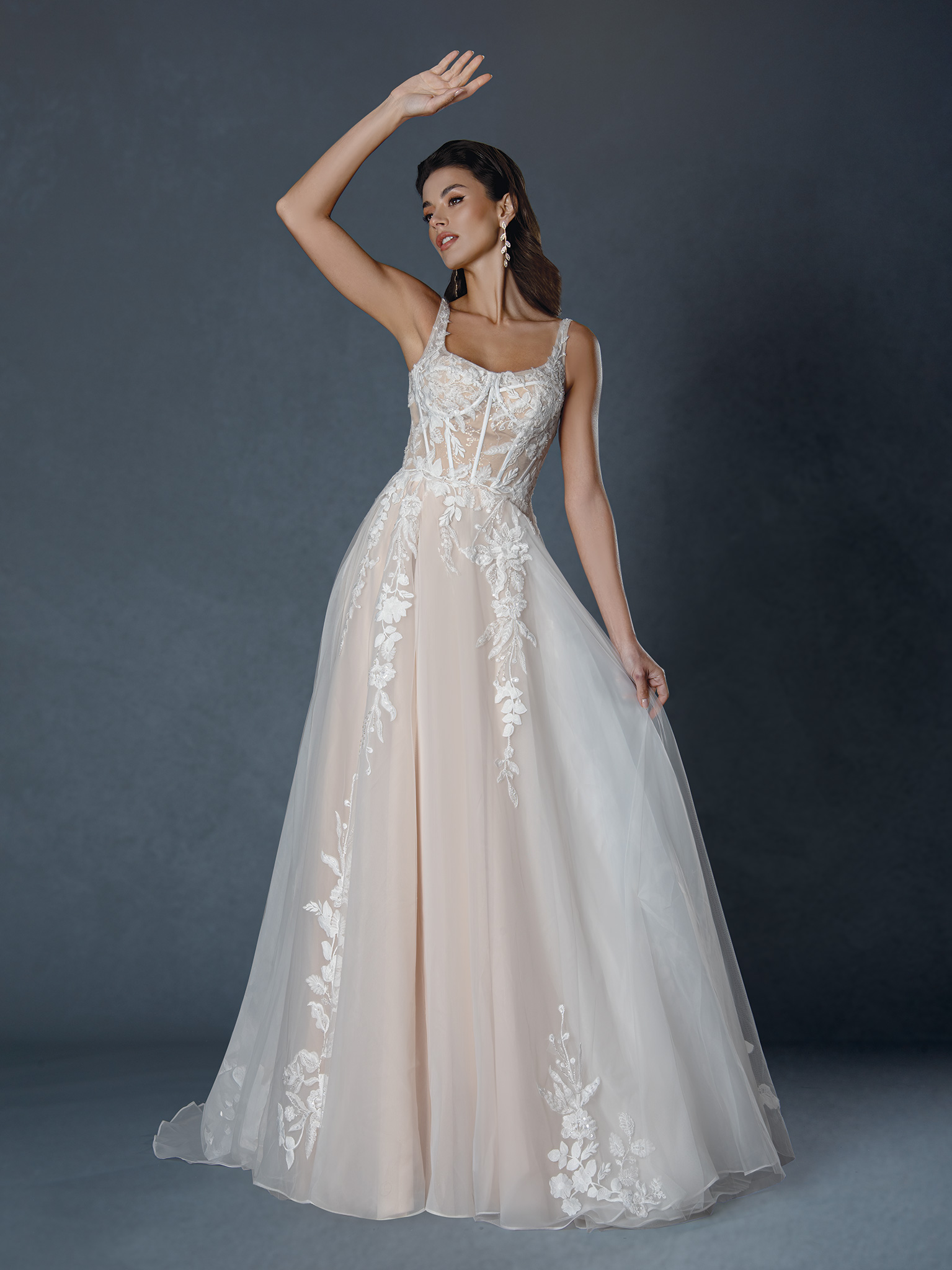 Light, romantic, and effortlessly ethereal. This A-line gown features delicate floral lace appliqués over a soft nude un