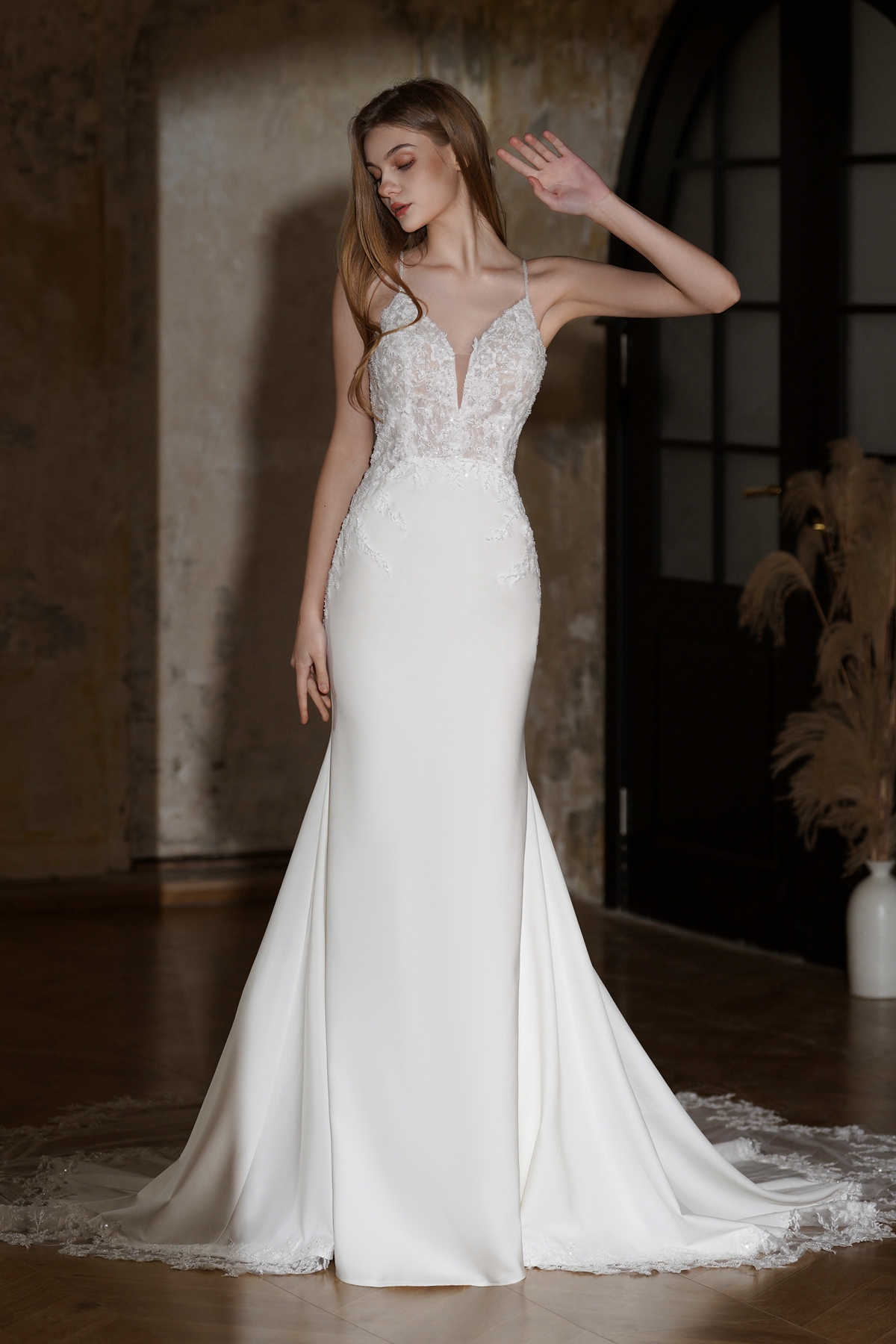 Elegant and modern, this crepe wedding dress features a plunging illusion neckline, delicate lace bodice, and a figure-h