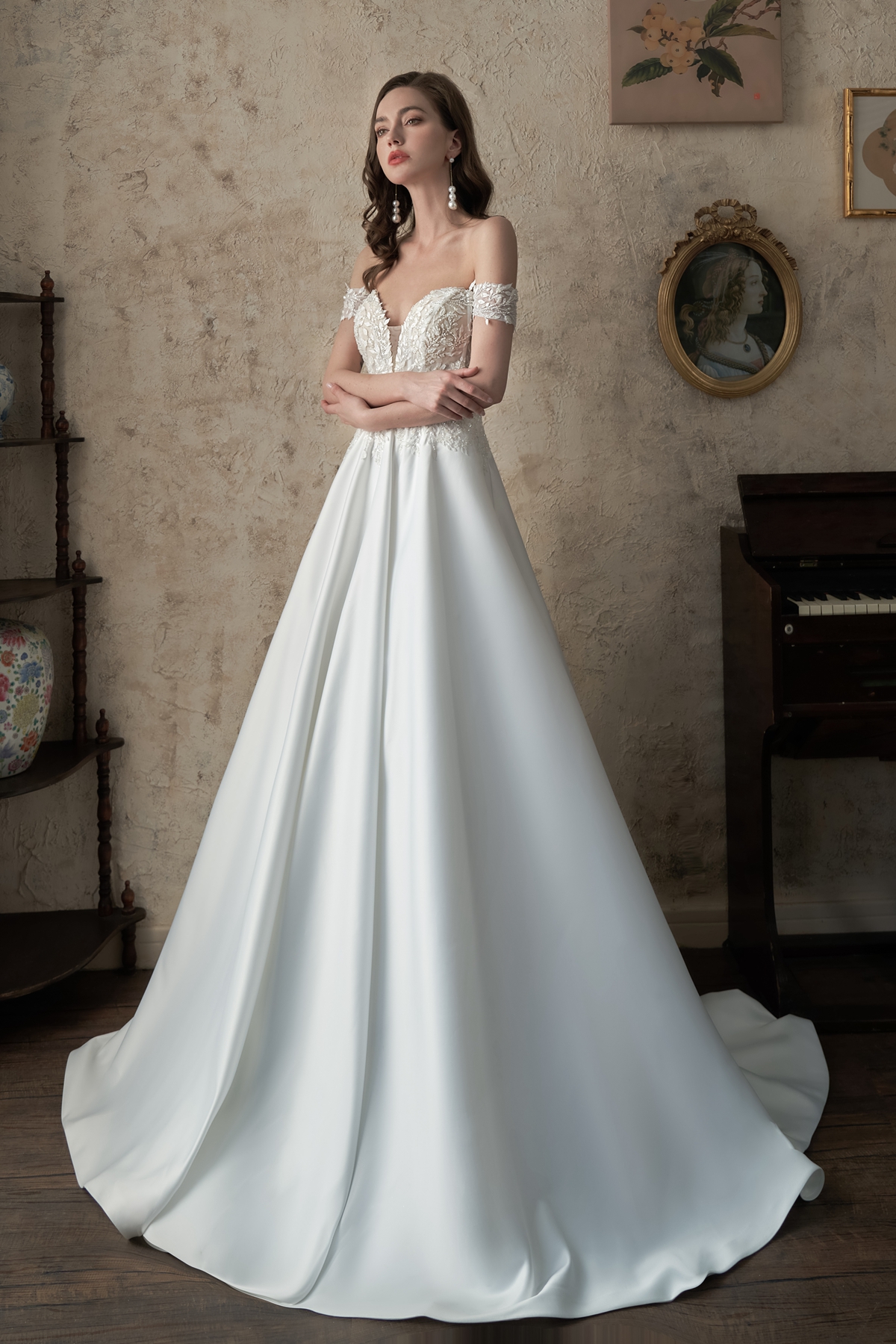 A vision of timeless beauty, this off-the-shoulder ball gown features a structured bodice adorned with delicate lace and