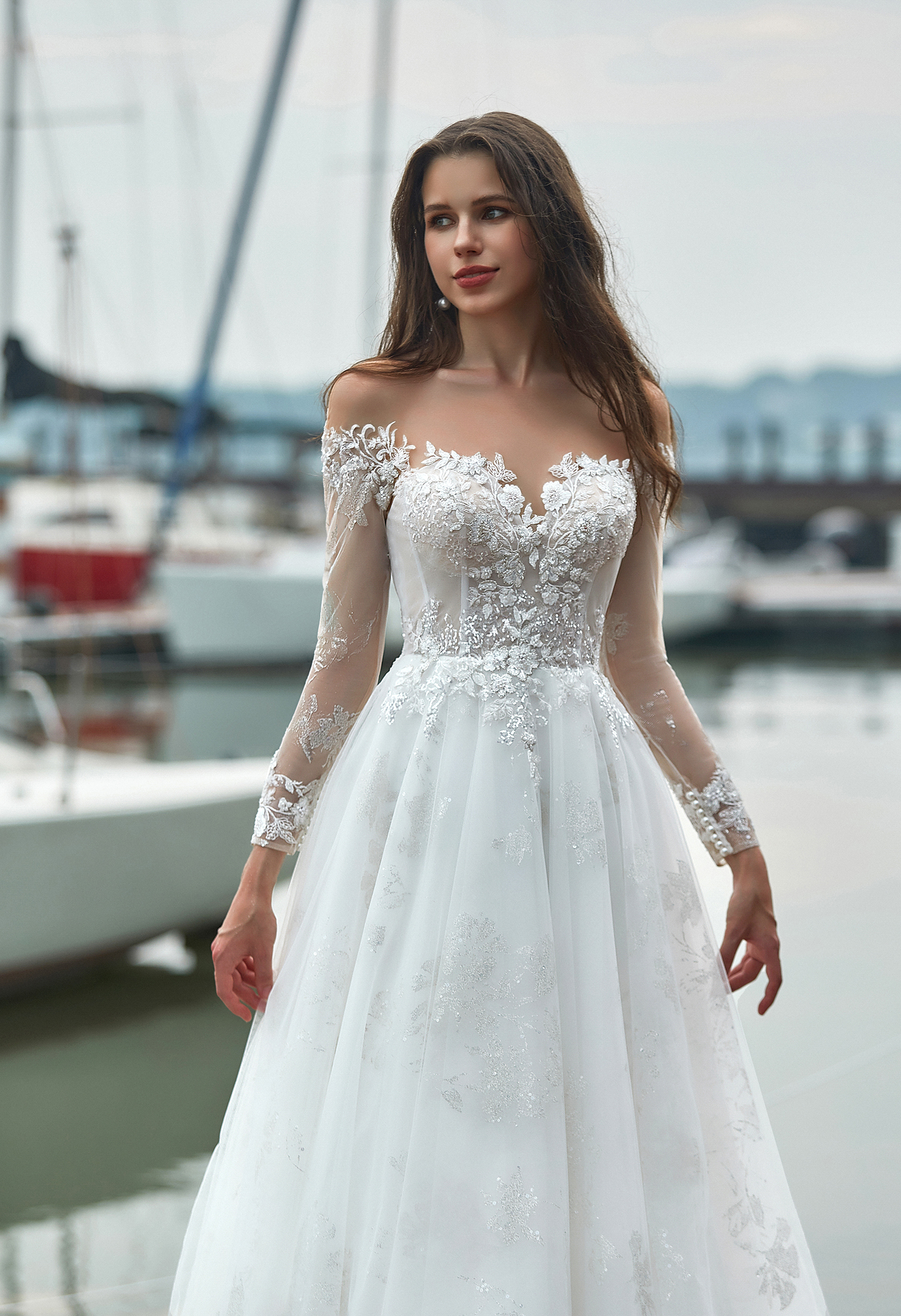 A dreamy off-shoulder wedding gown featuring illusion lace sleeves and a soft A-line skirt. Perfect for brides who love 