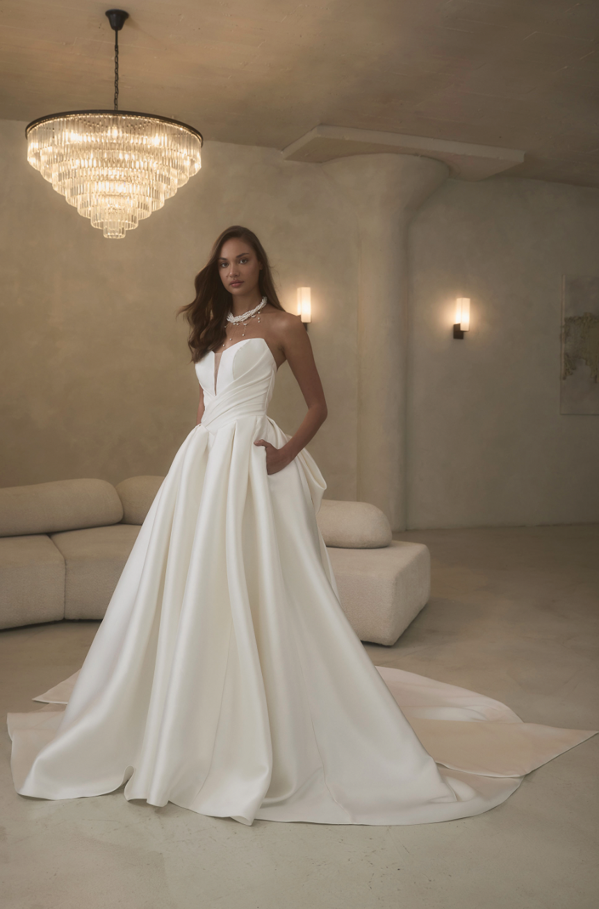 Sculpted and effortlessly chic, this strapless satin ball gown features a structured bodice, pleated skirt, and hidden p