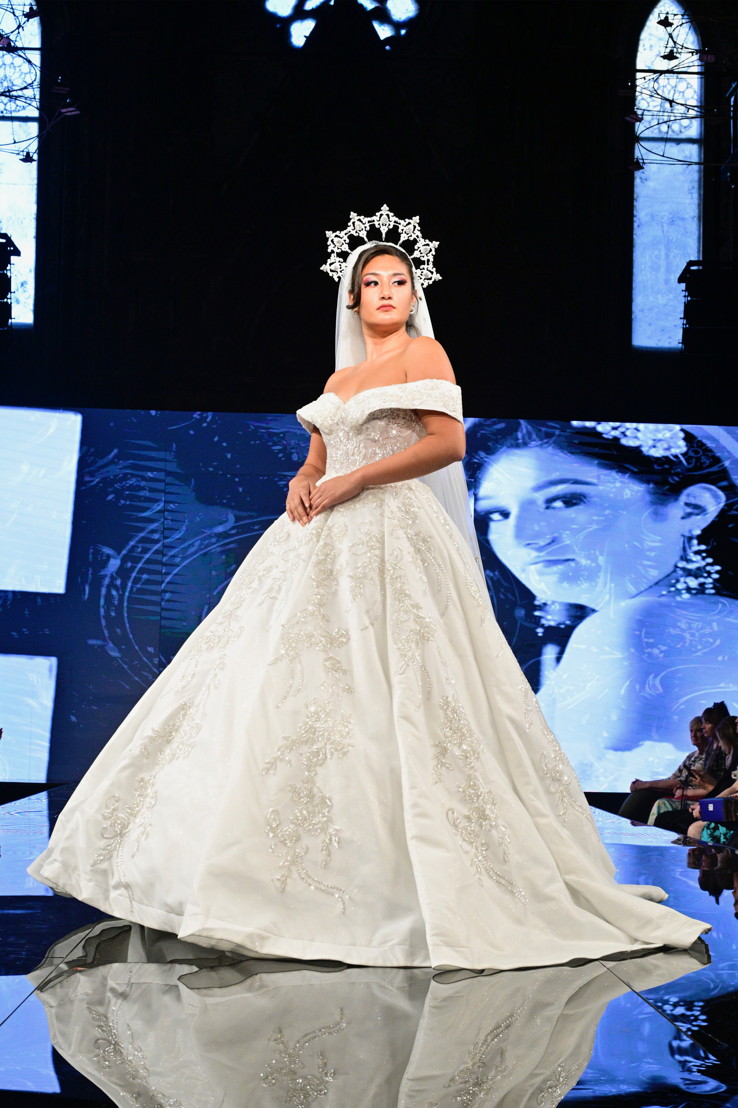 Make your grand entrance in this regal off-shoulder ball gown featuring ornate beaded embroidery, shimmering satin, and 