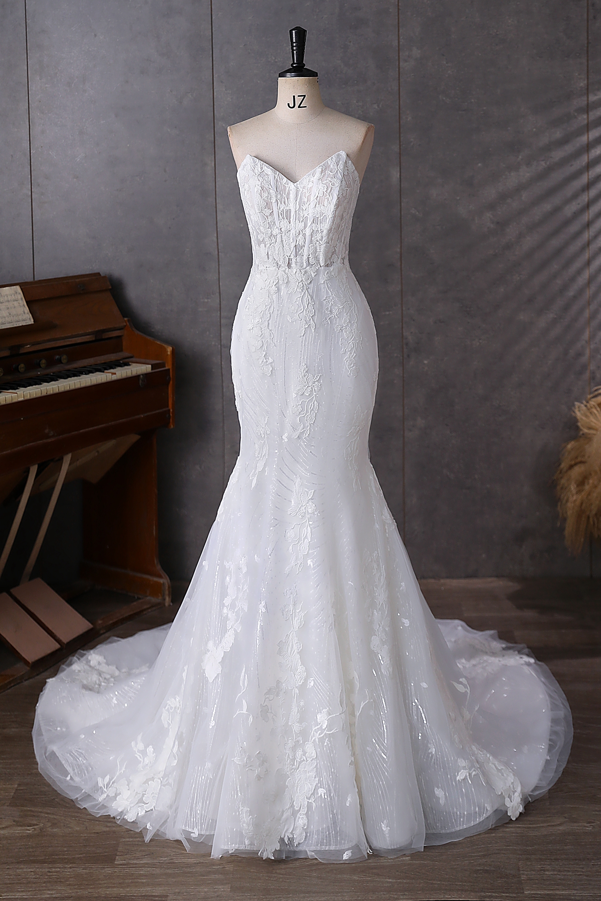Effortlessly chic and sultry, this strapless mermaid gown features a sculpted lace bodice, sheer detailing, and a dramat