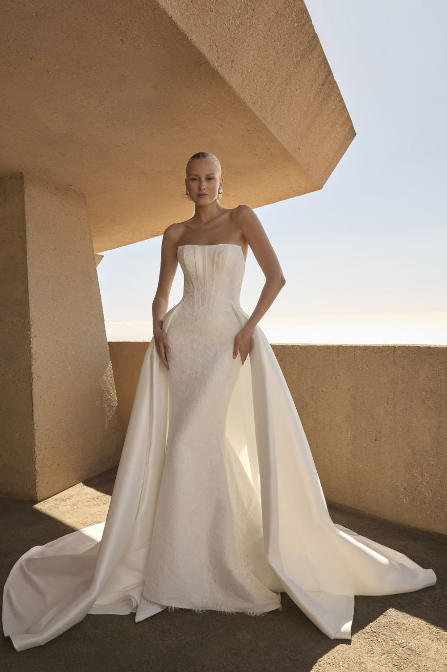 Modern minimalism meets raw elegance in this stunner. Showcasing a sleek, strapless fit-and-flare silhouette, her pointe