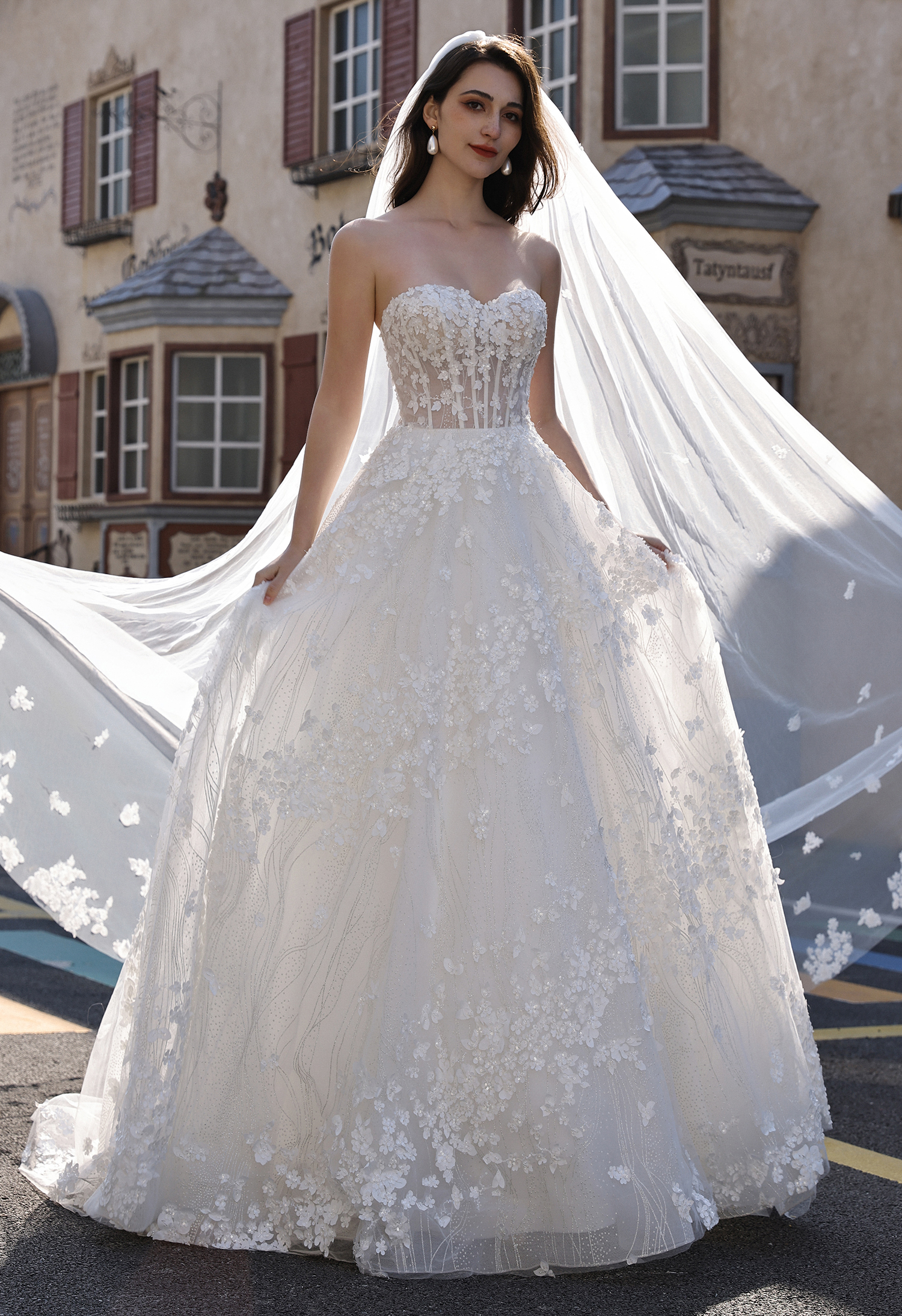 This floral ball gown wedding dress features a structured corset bodice, dimensional floral appliqués, and a full romant
