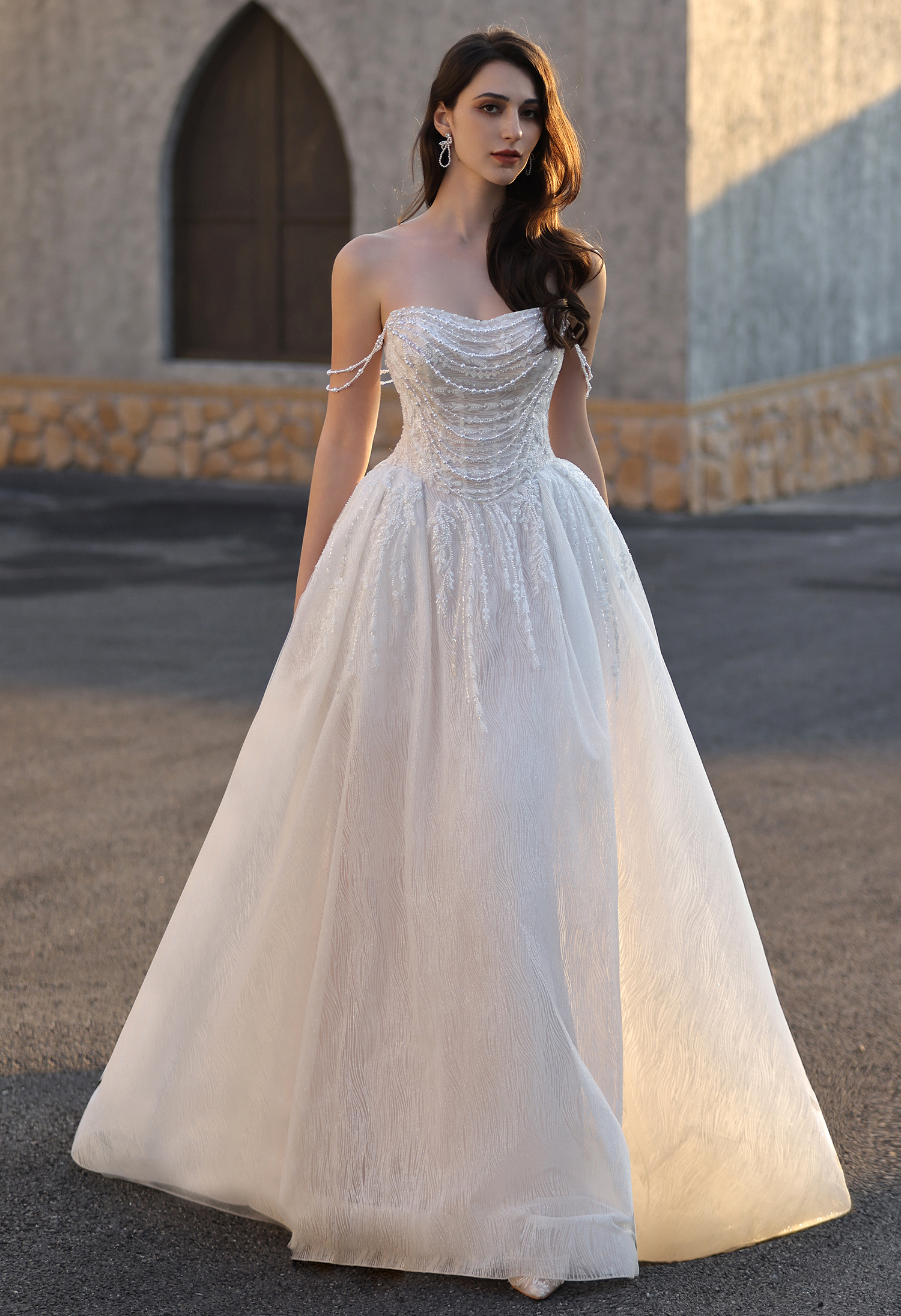 This strapless beaded A-line wedding dress features a softly draped bodice with delicate beading and a flowing textured 